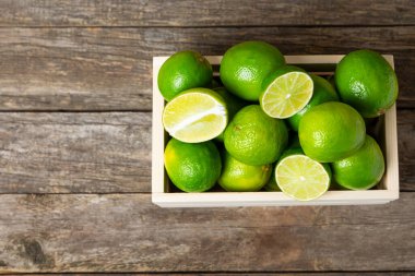 Tahta bir masada taze kireç. Masadaki bütün limon ve dilimler bir kasede. Citrus. C vitamini diyeti. Tropik meyveler. Yaz ferahlatıcı limonata ya da mojito konsepti. Mesaj için yer var. Boşluğu kopyala.