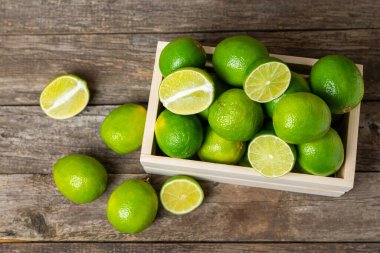 Tahta bir masada taze kireç. Masadaki bütün limon ve dilimler bir kasede. Citrus. C vitamini diyeti. Tropik meyveler. Yaz ferahlatıcı limonata ya da mojito konsepti. Mesaj için yer var. Boşluğu kopyala.