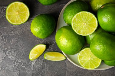 Tahta bir masada taze kireç. Masadaki bütün limon ve dilimler bir kasede. Citrus. C vitamini diyeti. Tropik meyveler. Yaz ferahlatıcı limonata ya da mojito konsepti. Mesaj için yer var. Boşluğu kopyala.