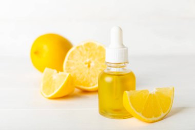 Limon dilimlenmiş limonlu bir şişede limon yağı ve ahşap bir arka planda yapraklar. Limon yağı. Aromatik esanslı parfüm şişesi. Serum, limon özü. C vitamini. Doğal kozmetik ürünler. Aromaterapi. Spa mı? Metin için boşluk.