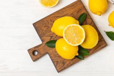 Tahta bir masada limon. Bir dilim taze limon. Turunçgil yapraklı taze limon. Limon suyu. Yemek ve içecek malzemeleri hazırlanıyor. Sağlıklı beslenme. Metin için C vitamini alanı.