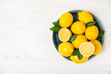 Tahta bir masada limon. Bir dilim taze limon. Turunçgil yapraklı taze limon. Limon suyu. Yemek ve içecek malzemeleri hazırlanıyor. Sağlıklı beslenme. Metin için C vitamini alanı.