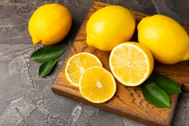 Tahta bir masada limon. Bir dilim taze limon. Turunçgil yapraklı taze limon. Limon suyu. Yemek ve içecek malzemeleri hazırlanıyor. Sağlıklı beslenme. Metin için C vitamini alanı.