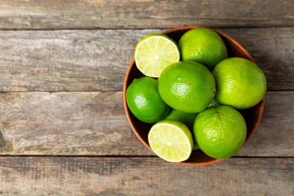 Tahta bir masada taze kireç. Masadaki bütün limon ve dilimler bir kasede. Citrus. C vitamini diyeti. Tropik meyveler. Yaz ferahlatıcı limonata ya da mojito konsepti. Mesaj için yer var. Boşluğu kopyala.