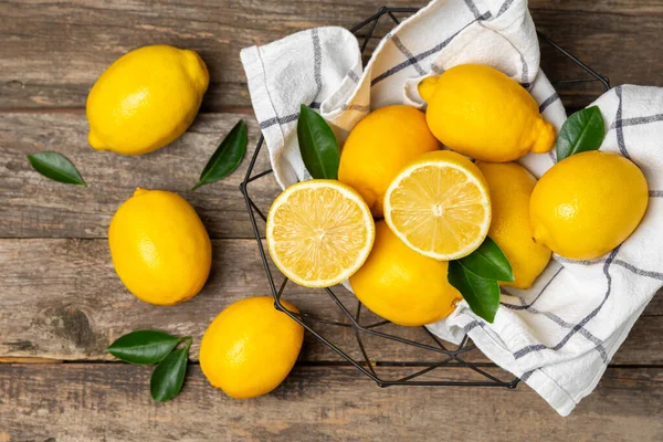 Tahta bir masada limon. Bir dilim taze limon. Turunçgil yapraklı taze limon. Limon suyu. Yemek ve içecek malzemeleri hazırlanıyor. Sağlıklı beslenme. Metin için C vitamini alanı.