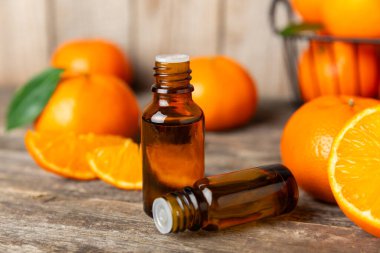 Tahta bir masada mandalina yağı. Bir şişe turunçgil yağı ve dilimlenmiş meyve. Mandalina kokulu mandalina yağı. Spa tedavileri için kozmetik yağı. Aromaterapi konsepti. Doğal kozmetikler. Geleneksel tıp. Metin için boşluk.