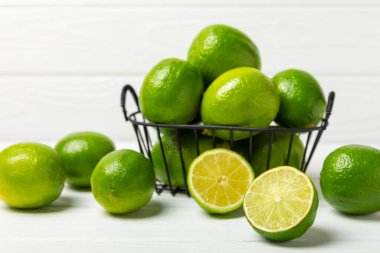 Tahta bir masada taze kireç. Masadaki bütün limon ve dilimler bir kasede. Citrus. C vitamini diyeti. Tropik meyveler. Yaz ferahlatıcı limonata ya da mojito konsepti. Mesaj için yer var. Boşluğu kopyala.