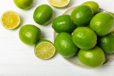 Tahta bir masada taze kireç. Masadaki bütün limon ve dilimler bir kasede. Citrus. C vitamini diyeti. Tropik meyveler. Yaz ferahlatıcı limonata ya da mojito konsepti. Mesaj için yer var. Boşluğu kopyala.