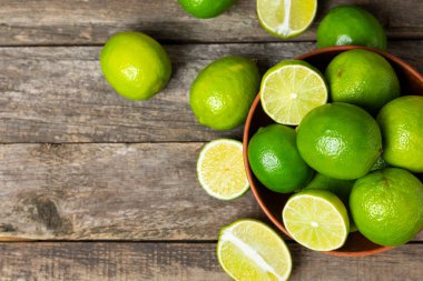 Tahta bir masada taze kireç. Masadaki bütün limon ve dilimler bir kasede. Citrus. C vitamini diyeti. Tropik meyveler. Yaz ferahlatıcı limonata ya da mojito konsepti. Mesaj için yer var. Boşluğu kopyala.