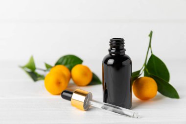 Tahta bir masada mandalina yağı. Bir şişe turunçgil yağı ve dilimlenmiş meyve. Mandalina kokulu mandalina yağı. Spa tedavileri için kozmetik yağı. Aromaterapi konsepti. Doğal kozmetikler. Geleneksel tıp. Metin için boşluk.