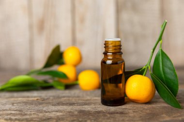 Tahta bir masada mandalina yağı. Bir şişe turunçgil yağı ve dilimlenmiş meyve. Mandalina kokulu mandalina yağı. Spa tedavileri için kozmetik yağı. Aromaterapi konsepti. Doğal kozmetikler. Geleneksel tıp. Metin için boşluk.
