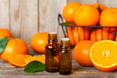 Tahta bir masada mandalina yağı. Bir şişe turunçgil yağı ve dilimlenmiş meyve. Mandalina kokulu mandalina yağı. Spa tedavileri için kozmetik yağı. Aromaterapi konsepti. Doğal kozmetikler. Geleneksel tıp. Metin için boşluk.