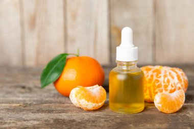 Tahta bir masada mandalina yağı. Bir şişe turunçgil yağı ve dilimlenmiş meyve. Mandalina kokulu mandalina yağı. Spa tedavileri için kozmetik yağı. Aromaterapi konsepti. Doğal kozmetikler. Geleneksel tıp. Metin için boşluk.