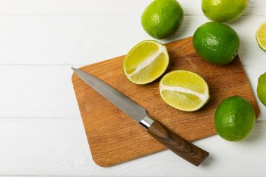 Tahta bir masada taze kireç. Masadaki bütün limon ve dilimler bir kasede. Citrus. C vitamini diyeti. Tropik meyveler. Yaz ferahlatıcı limonata ya da mojito konsepti. Mesaj için yer var. Boşluğu kopyala.