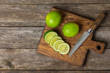 Tahta bir masada taze kireç. Masadaki bütün limon ve dilimler bir kasede. Citrus. C vitamini diyeti. Tropik meyveler. Yaz ferahlatıcı limonata ya da mojito konsepti. Mesaj için yer var. Boşluğu kopyala.