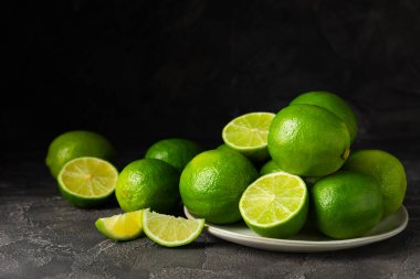 Tahta bir masada taze kireç. Masadaki bütün limon ve dilimler bir kasede. Citrus. C vitamini diyeti. Tropik meyveler. Yaz ferahlatıcı limonata ya da mojito konsepti. Mesaj için yer var. Boşluğu kopyala.
