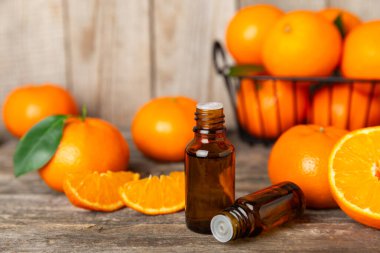 Tahta bir masada mandalina yağı. Bir şişe turunçgil yağı ve dilimlenmiş meyve. Mandalina kokulu mandalina yağı. Spa tedavileri için kozmetik yağı. Aromaterapi konsepti. Doğal kozmetikler. Geleneksel tıp. Metin için boşluk.