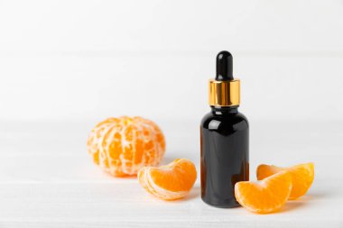 Tahta bir masada mandalina yağı. Bir şişe turunçgil yağı ve dilimlenmiş meyve. Mandalina kokulu mandalina yağı. Spa tedavileri için kozmetik yağı. Aromaterapi konsepti. Doğal kozmetikler. Geleneksel tıp. Metin için boşluk.