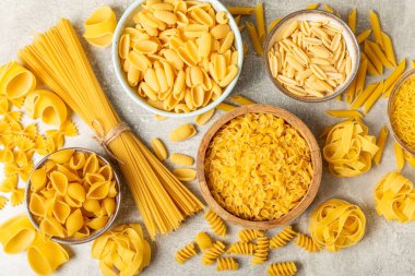 Arka plandaki kaselerde pişmemiş İtalyan makarnası çeşitleri. Kuru makarna çeşitleri, üst manzara, yemek arka planı. Farklı türde pişmemiş makarna. Malzemeler. Fırında pişmemiş İtalyan makarnası.