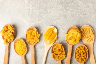 Arka plandaki kaselerde pişmemiş İtalyan makarnası çeşitleri. Kuru makarna çeşitleri, üst manzara, yemek arka planı. Farklı türde pişmemiş makarna. Malzemeler. Fırında pişmemiş İtalyan makarnası.