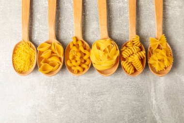 Kavanozda pişmemiş makarna. Arka planda çeşitli İtalyan kuru makarna şekilleri, üst görünüm. Yemek geçmişi. Makarna çeşitleri. çiğ makarna