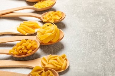 Kavanozda pişmemiş makarna. Arka planda çeşitli İtalyan kuru makarna şekilleri, üst görünüm. Yemek geçmişi. Makarna çeşitleri. çiğ makarna