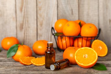 Tahta bir masada mandalina yağı. Bir şişe turunçgil yağı ve dilimlenmiş meyve. Mandalina kokulu mandalina yağı. Spa tedavileri için kozmetik yağı. Aromaterapi konsepti. Doğal kozmetikler. Geleneksel tıp. Metin için boşluk.