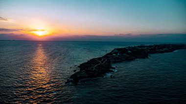 Mujeres Adası, Cancun, Meksika - Okyanus sakin ve güneş batıyor, güzel ve sakin bir atmosfer yaratıyor. Su koyu mavi bir renktir ve gökyüzü turuncu ve pembe renklerin bir karışımıdır. Sahne huzurlu ve rahatlatıcı.