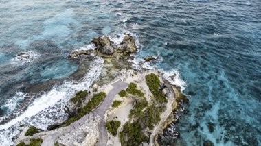 Isla Mujeres, Cancun, Meksika - Rocky kıyıları, arkasında mavi bir okyanus var. Okyanus sakin ve kayalar tüm bölgeye dağılmış durumda.