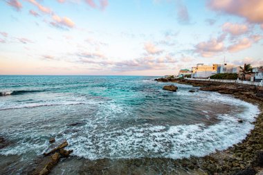Isla Mujeres, Cancun, Meksika arkasında küçük bir kasaba olan güzel bir sahil. Gökyüzü mavi ve pembenin bir karışımıdır. Huzurlu ve huzurlu bir atmosfer yaratır.