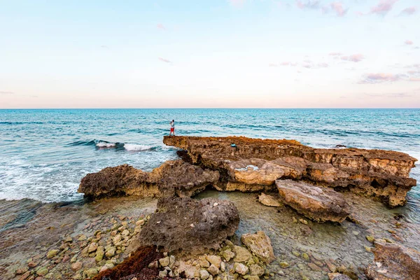 Isla Mujeres, Cancun, Meksika kayanın üzerinde duran bir adamla Rocky sahilleri. Gökyüzü mavi ve su sakin.