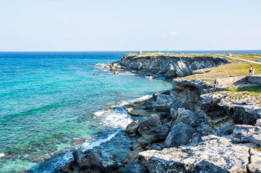 Isla Mujeres, Cancun, Meksika Rocky kıyıları, arkasında mavi bir okyanus var. Okyanus sakin ve kayalar pürüzlü.