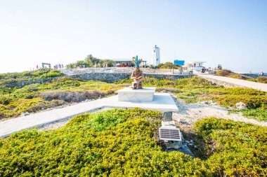Isla Mujeres, Cancun, Meksika heykeli yemyeşil bir arazide taş bir heykel üzerinde oturuyor. Heykel bir patikayla çevrili ve bir grup insan onun üzerinde yürüyor. Sükunet ve huzur kavramı
