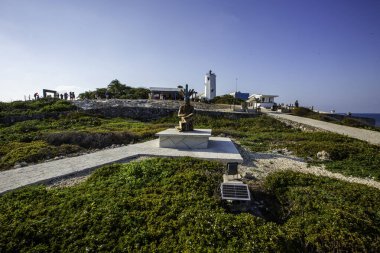 Isla Mujeres, Cancun, Meksika heykeli yemyeşil bir arazide taş bir heykel üzerinde oturuyor. Heykel çeşitli bitki ve ağaçlarla çevrili ve huzurlu bir atmosfer yaratıyor. Saha sahile yakın.
