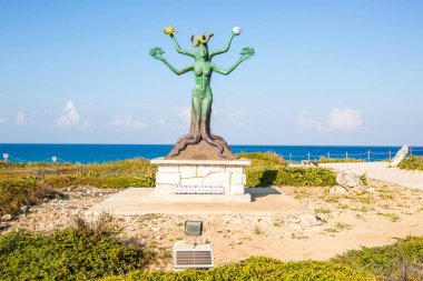 Isla Mujeres, Cancun, Meksika heykeli elinde ağaç gövdesi olan bir kadın. Heykel yeşil ve okyanusa yakın.