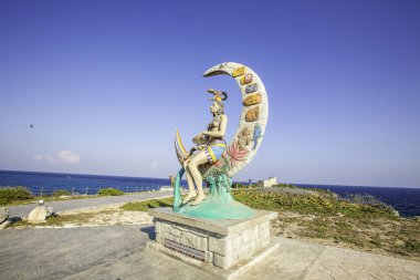 Isla Mujeres, Cancun, Meksika heykeli büyük, yuvarlak bir nesnenin üzerinde oturan bir kadın. Heykel bir sahil ve okyanusla çevrilidir.