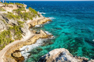 Isla Mujeres, Cancun, Mexico Rocky shoreline with a blue ocean in the background. The water is calm and the rocks are jagged