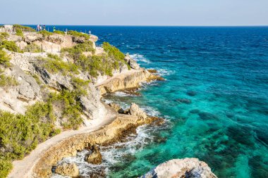 Isla Mujeres, Cancun, Mexico Beautiful blue ocean with a rocky shoreline. The water is calm and the sky is clear