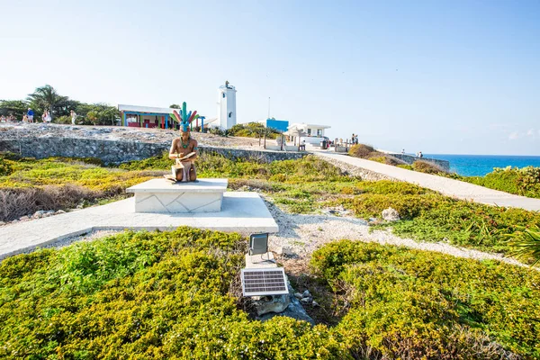 Isla Mujeres, Cancun, Meksika heykeli yemyeşil bir arazide bir heykel üzerinde oturuyor. Heykel bir patika ve arka planda bir plaj ile çevrilidir. Heykelle manzara huzurlu ve huzurlu.