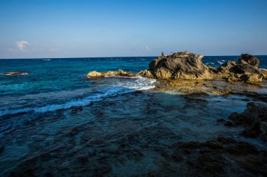 Isla Mujeres, Cancun, Mexico Rocky shoreline with a calm ocean in the background. The water is blue and the rocks are grey