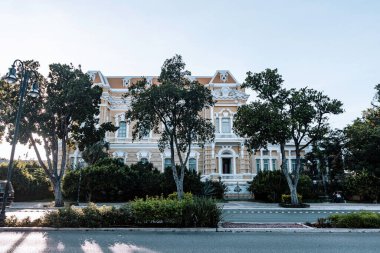 Merida, Yucatan, Meksika, Büyük, yeşil çatılı ve beyaz çizgili beyaz bir bina. Binanın bir sürü penceresi ve bir balkonu var. Sokaklar boş ve gökyüzü temiz.