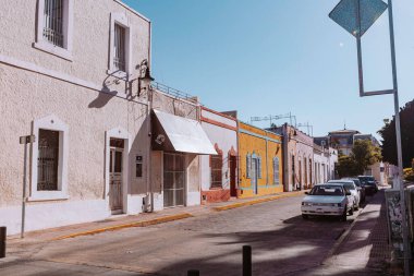 Merida, Yucatan, Meksika, Beyaz binalı ve kırmızı binalı bir cadde. Sokaklar boş ve güneş parlıyor.
