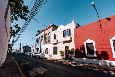 Merida, Yucatan, Meksika, kırmızı binası ve beyaz arabaları olan bir cadde. Sokaklar boş ve gökyüzü temiz.
