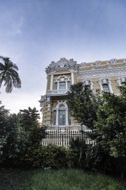 Merida, Yucatan, Meksika, önünde bir sürü pencere ve çit olan büyük bir bina. Bina sarı ve beyaz.