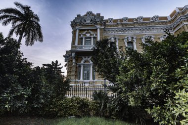 Merida, Yucatan, Meksika, önünde bir sürü ağaç olan büyük bir bina. Bina eski ve bir sürü penceresi var.