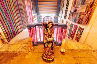 Merida, Yucatan, Meksika, İskelet heykeli renkli duvar halıları olan bir odada bir çıkıntının üzerinde duruyor. Odanın eşsiz ve eklektik bir stili var, farklı renk ve desenlerin karışımı. İskelet heykel gizem ve entrika katıyor 