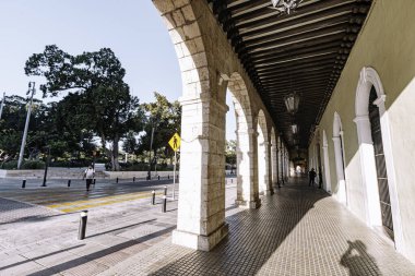 Merida, Yucatan, Meksika, yan tarafında sarı bir işaret olan uzun, dar bir patika. Geçit kemerli sütunlarla kaplı ve üzerinde yürüyen birkaç kişi var.