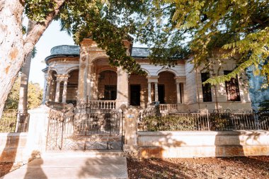 Merida, Yucatan, Meksika. Önünde beyaz çitli ve ağaç olan büyük bir ev. Evin bir sürü penceresi ve balkonu var.