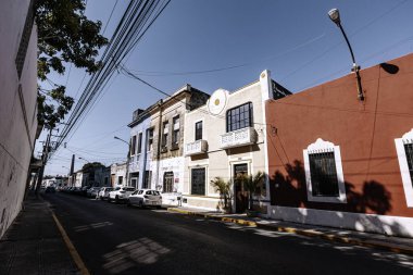 Merida, Yucatan, Meksika, kırmızı binası ve beyaz arabaları olan bir cadde. Sokaklar boş ve gökyüzü temiz.