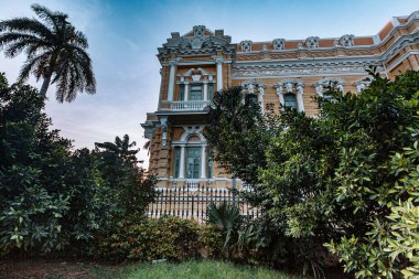Merida, Yucatan, Meksika, önünde bir sürü ağaç olan büyük bir bina. Bina eski ve bir sürü penceresi var.